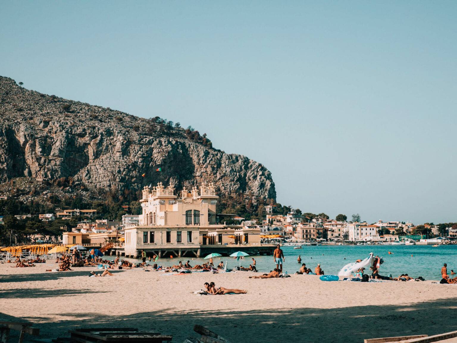 Blick auf den Strand von Mondello mit türkisblauen Wasser im Hintergrund.