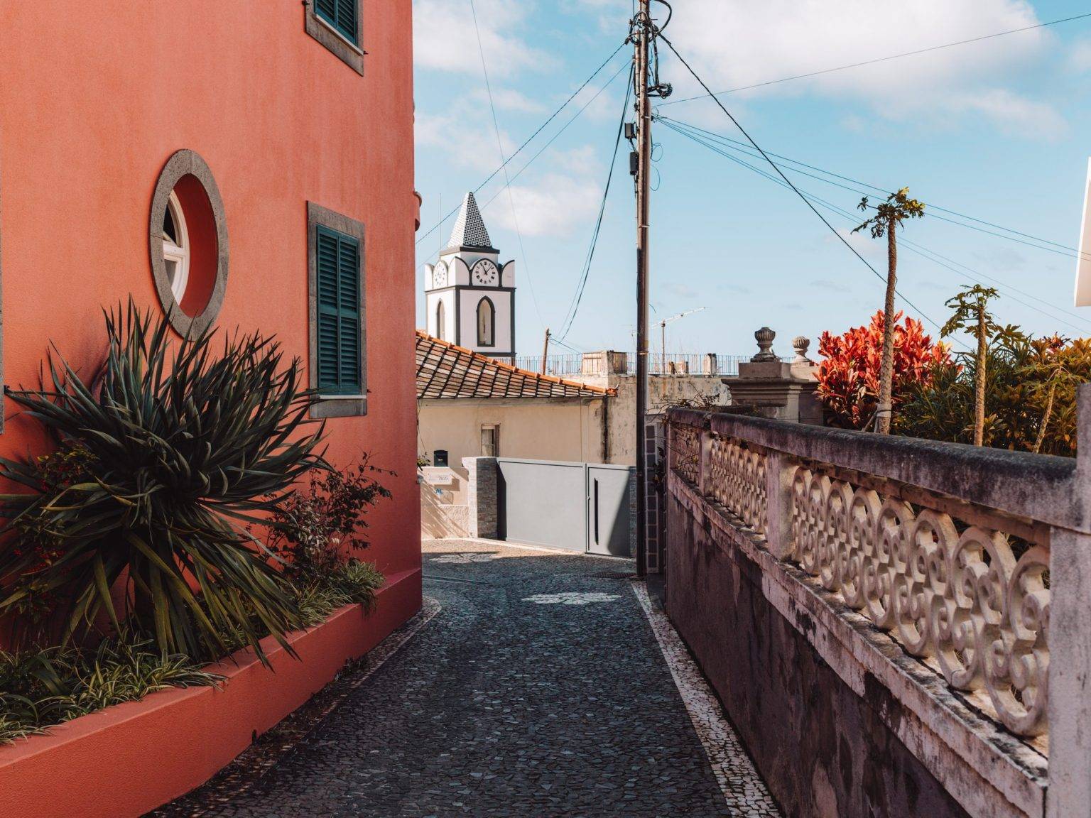 Eine kleine Gasse führt neben einem orangefarbenen Haus vorbei mit Blick auf den Horizont