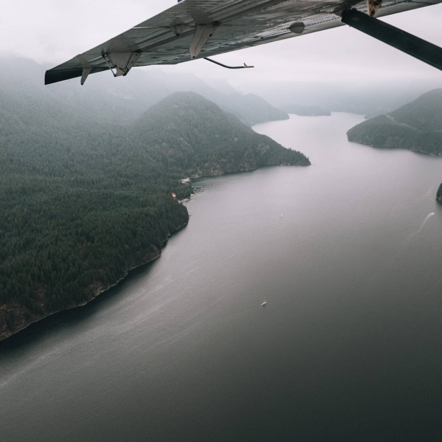 Der Blick aus dem Flugzeug auf einen breiten Fluss und eine grüne Hügellandschaft.