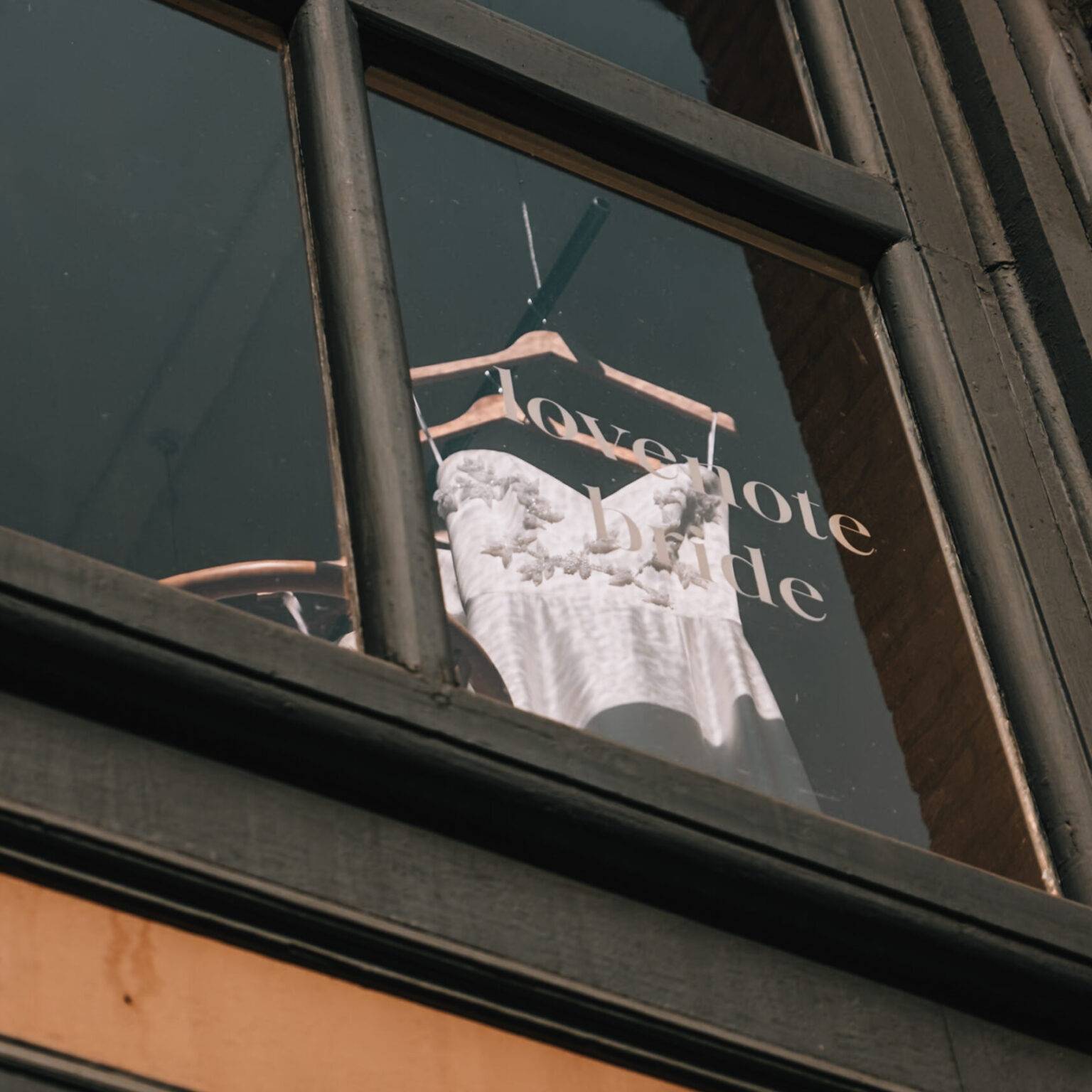 Ein Brautkleid hängt im Fenster des Ladens "lovenote bride".