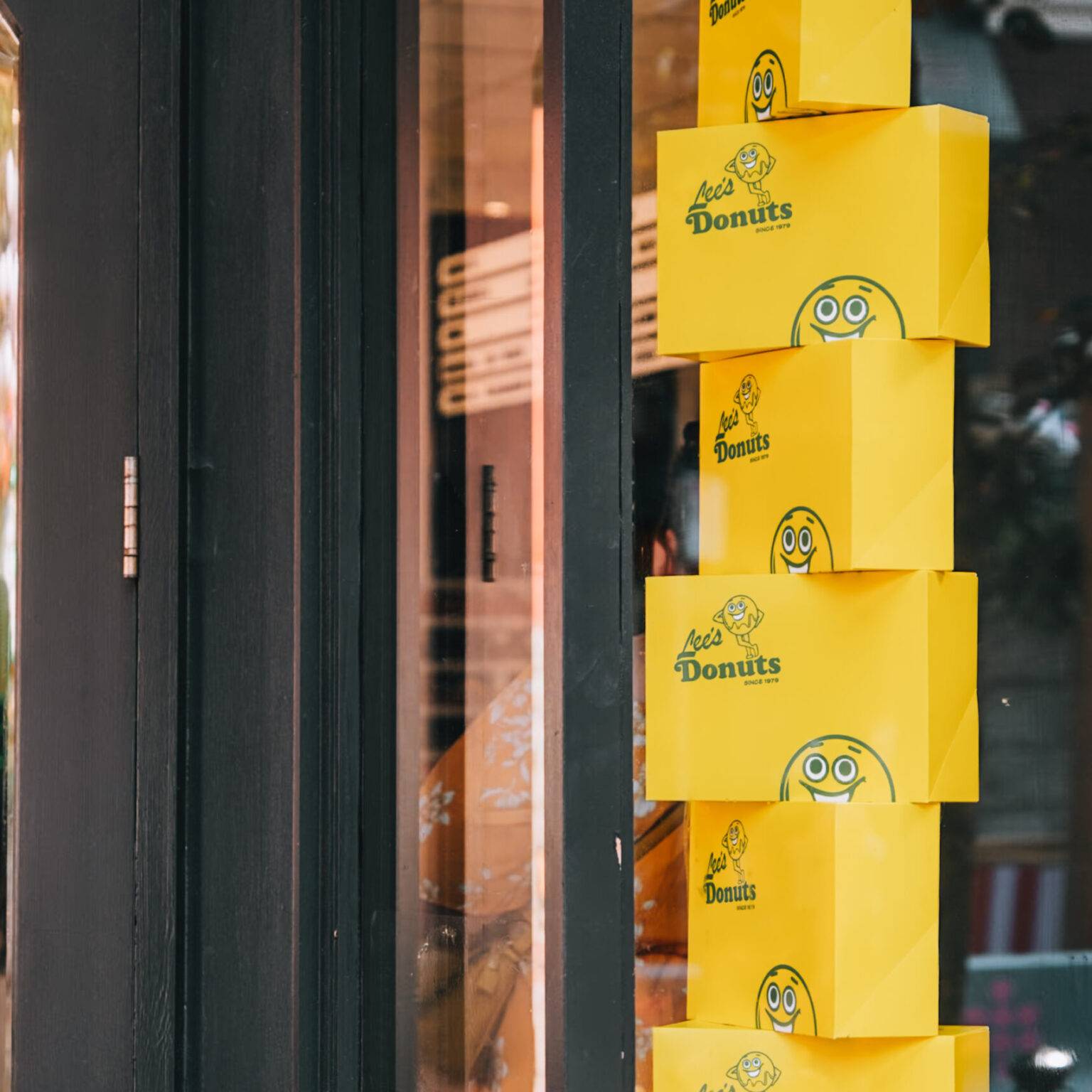 Das Schaufenster von Lee's Donuts, hinter dem ein Turm aus Donut-Boxen aufgestapelt ist.