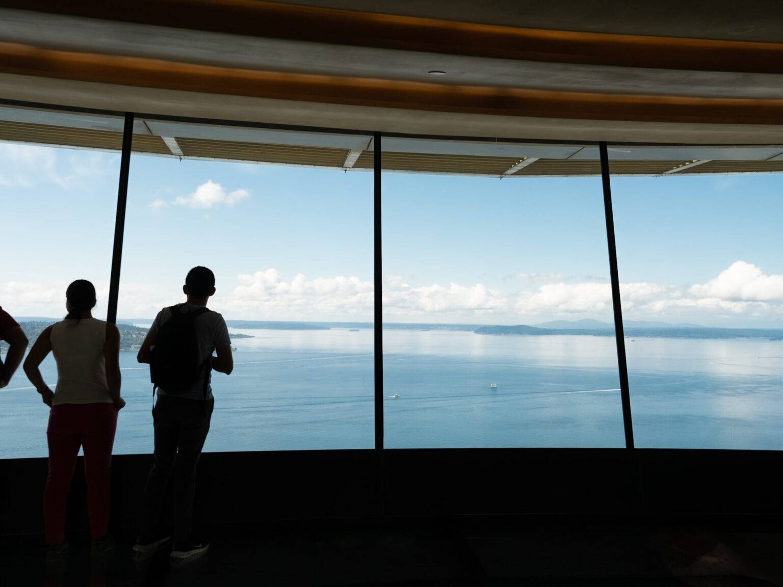 Ein paar Menschen stehen vor den Panoramafenstern der Space Needle.