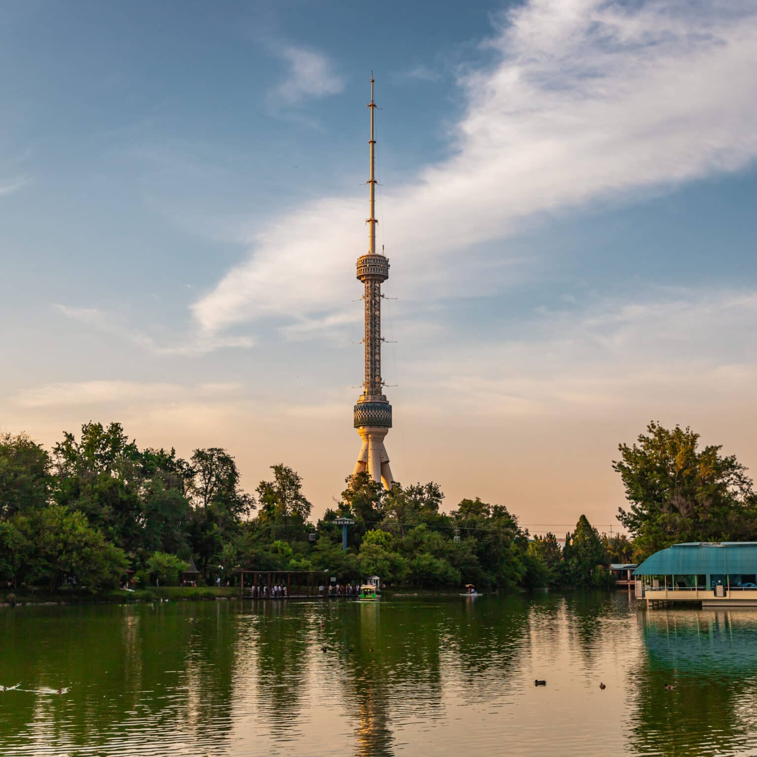 Der Tashkent TV-Tower spiegelt sich in einem See, umgeben von grünen Bäumen