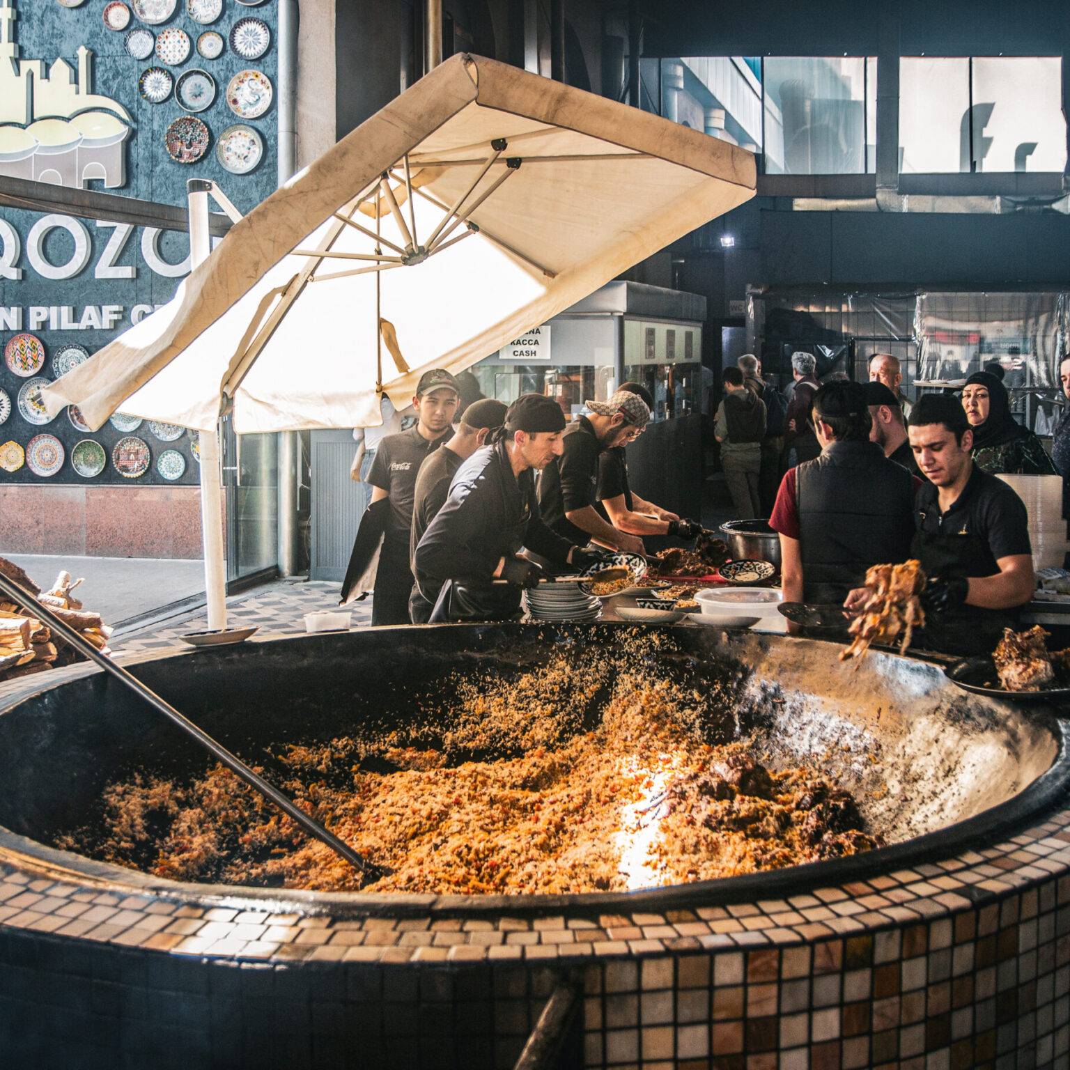 Köche bereiten in einem riesigen Kessel traditionelles Plov im Restaurant Besh-Qozon in Taschkent zu