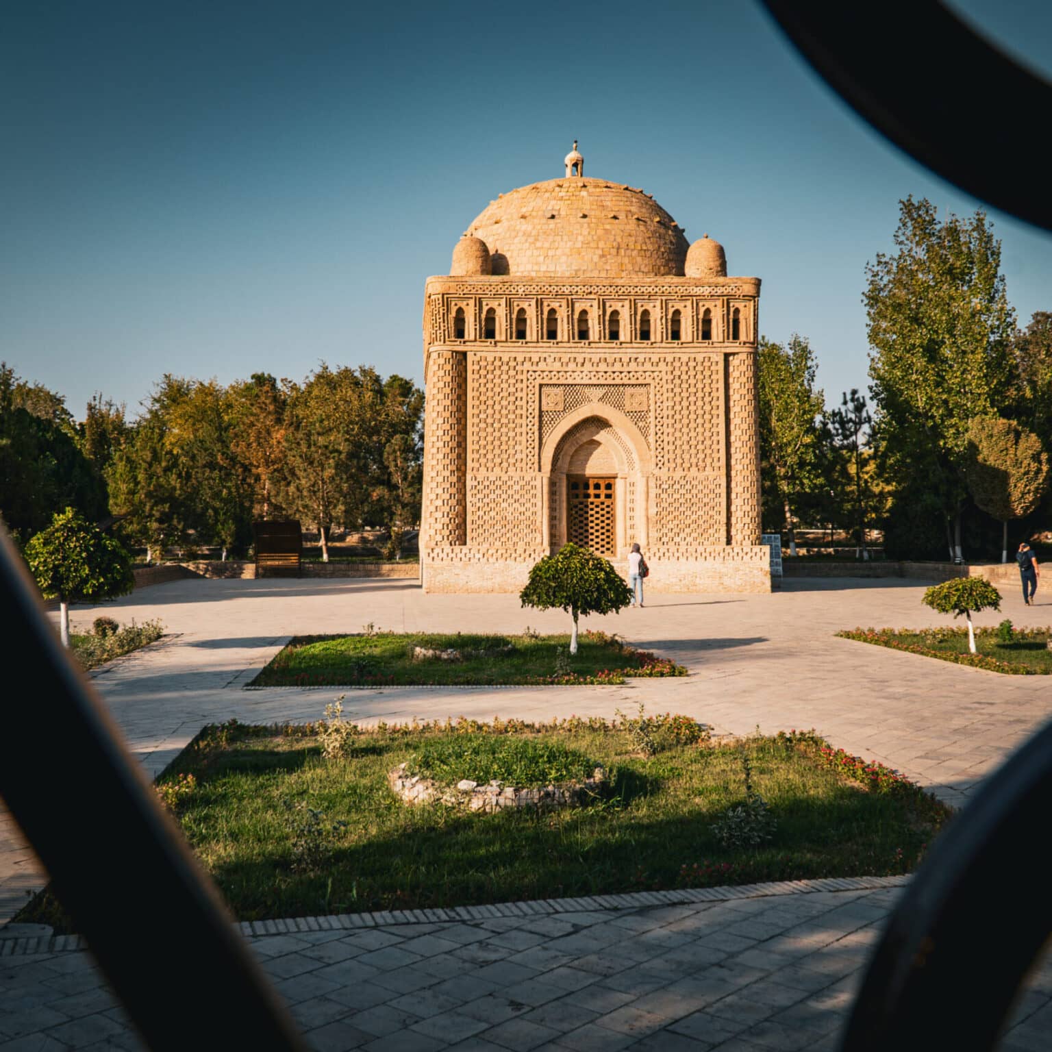 Das Samaniden-Mausoleum in Bukhara mit Architektur aus Ziegelsteinen, eingebettet in eine grüne Parkanlage im Licht des Nachmittags