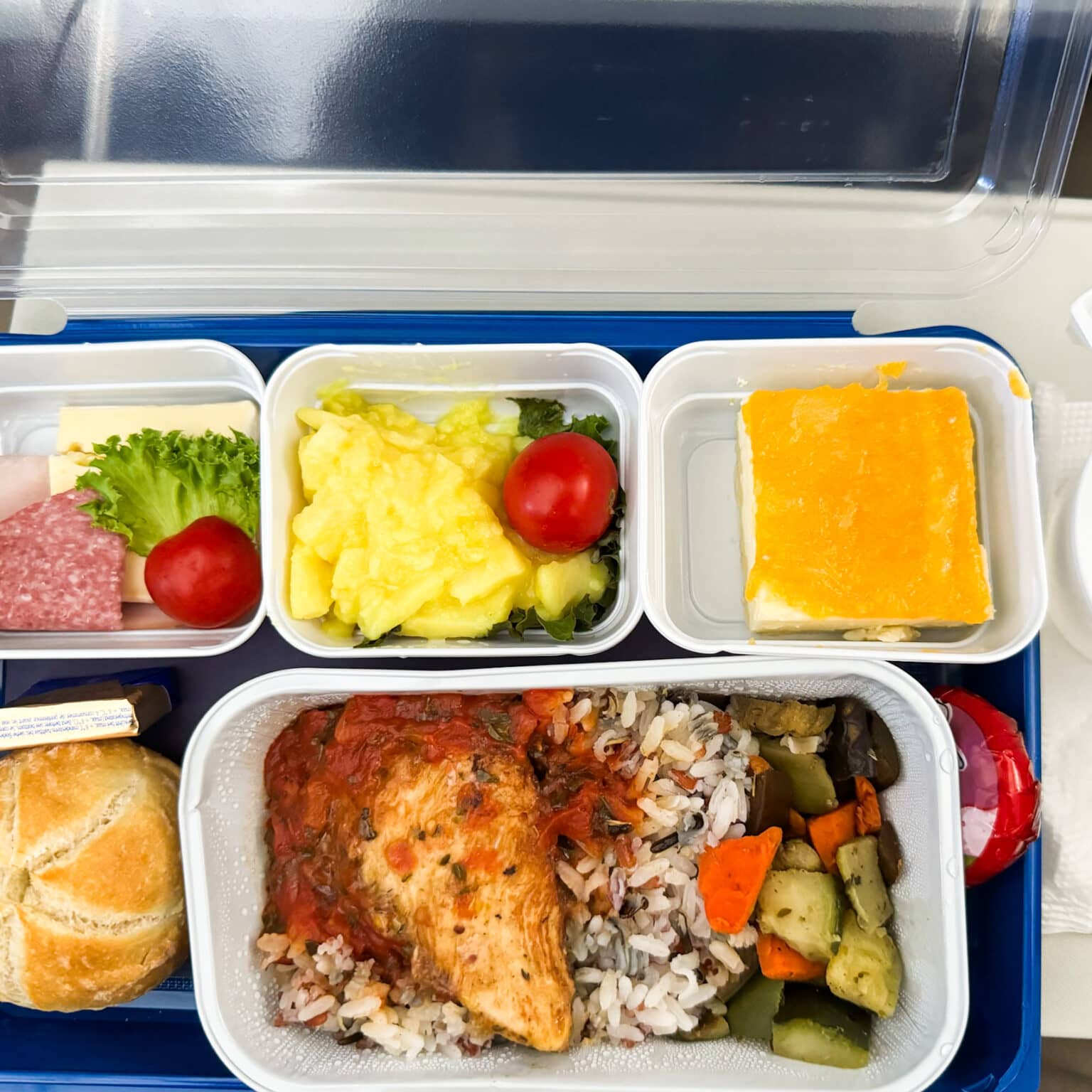 Das Bordmenü von Uzbekistan Airways mit Reis, Gemüse, Fleisch, einem Brötchen, Wurst und Käse, Kartoffelsalat und einem Stück Kuchen.