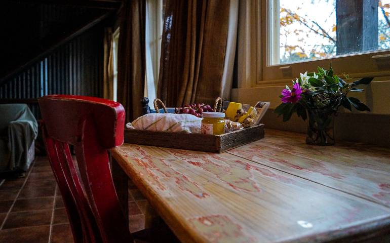 Im Blue Mountains Buttercup Barn ist auf einem Holztisch ein Tablett mit Frühstück und ein Blumenstrauß angerichtet.