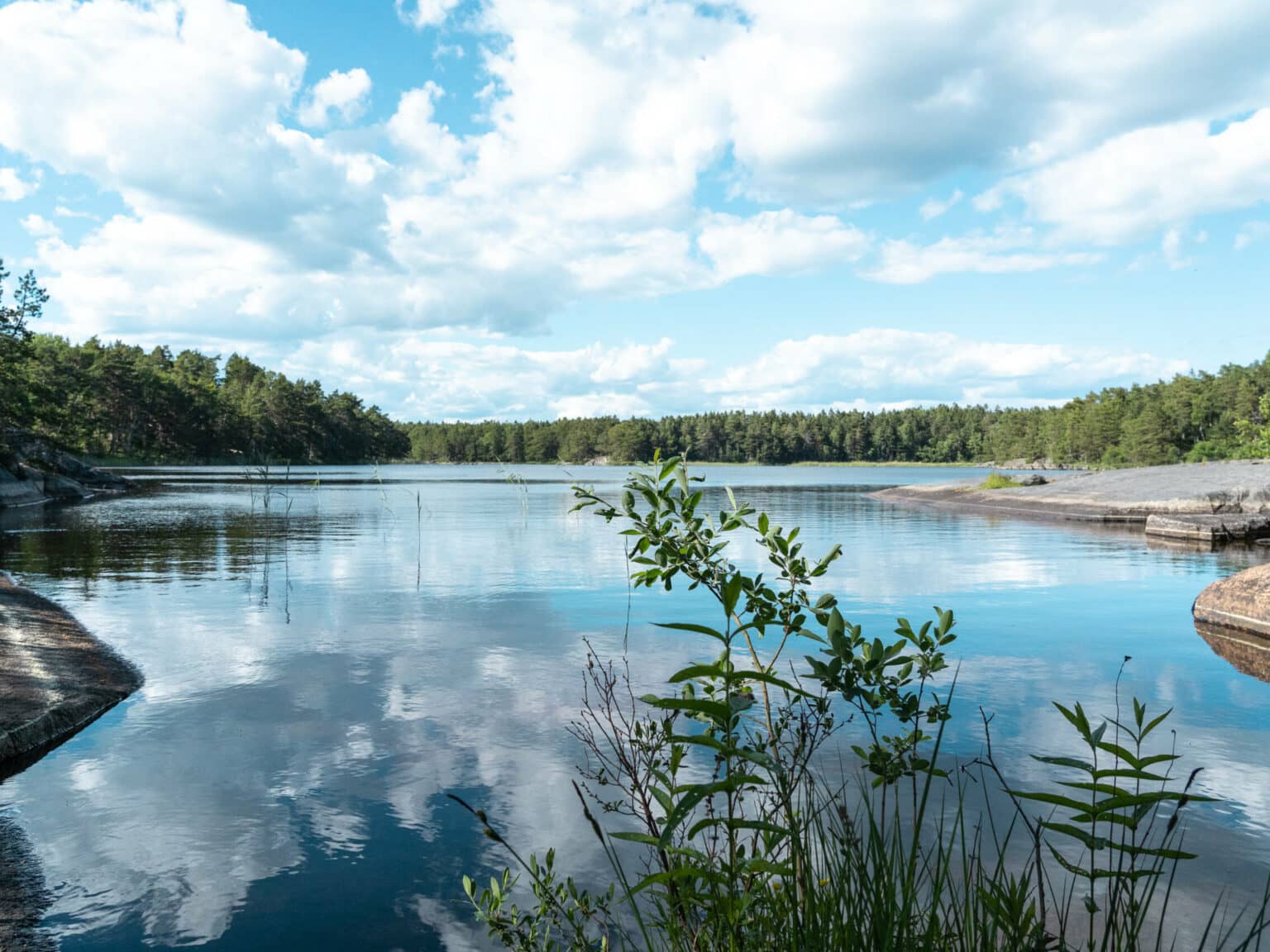 Ein idyllischer Binnensee mit tiefblauem Wasser, umrandet von grünen Nadelwäldern liegt auf der Schäreninsel Möja und lädt zum Baden ein.