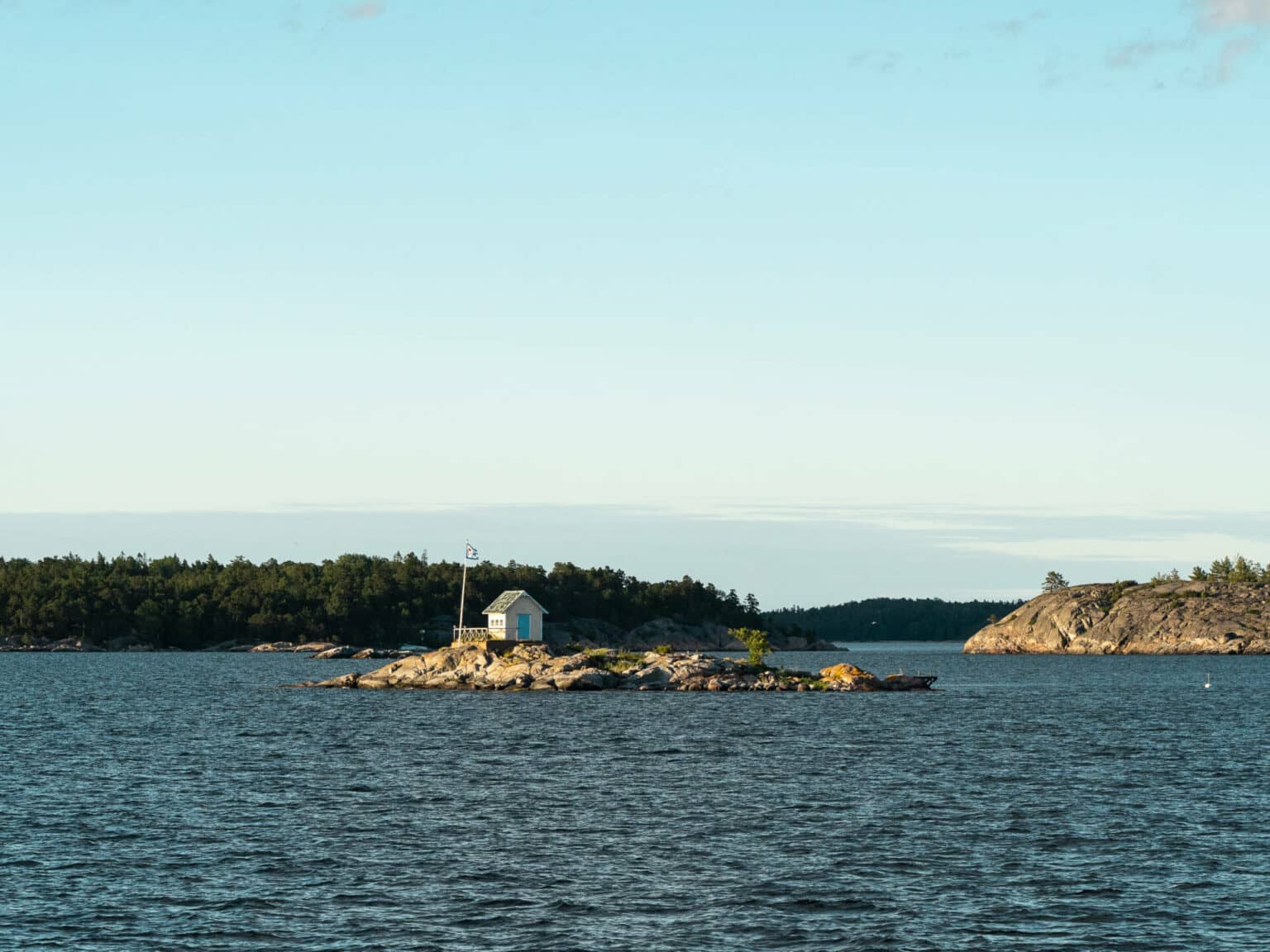 Auf einer winzigen, felsigen Insel des Schärengartens thront ein einsames Holzhäuschen.