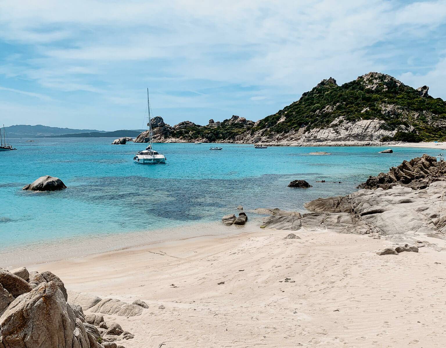 Einige Boote schwimmen vor den Ufern im Meer vor dem Norden von Sardinien.