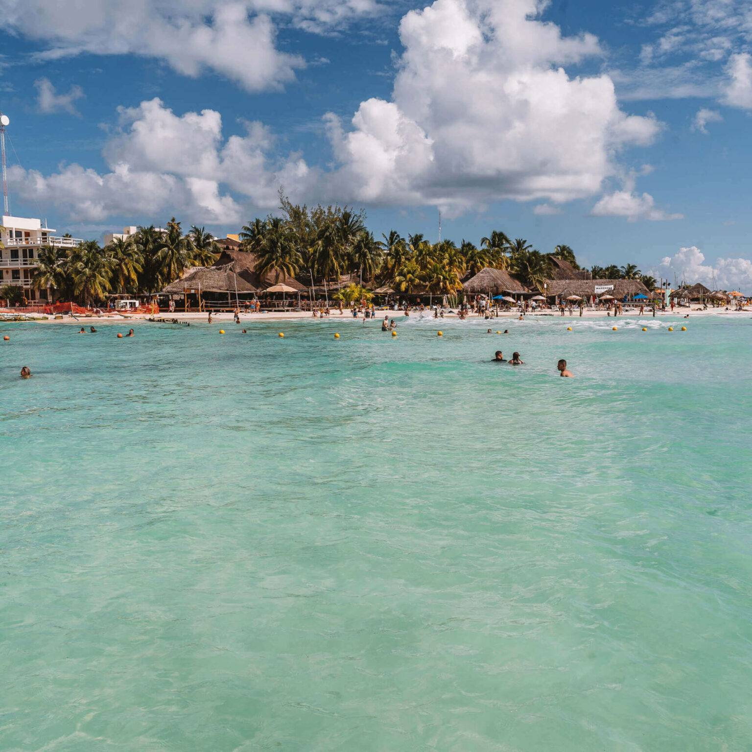 Menschen baden im türkisblauen Wasser am Playa Norte, einem Strand auf Yucatan.
