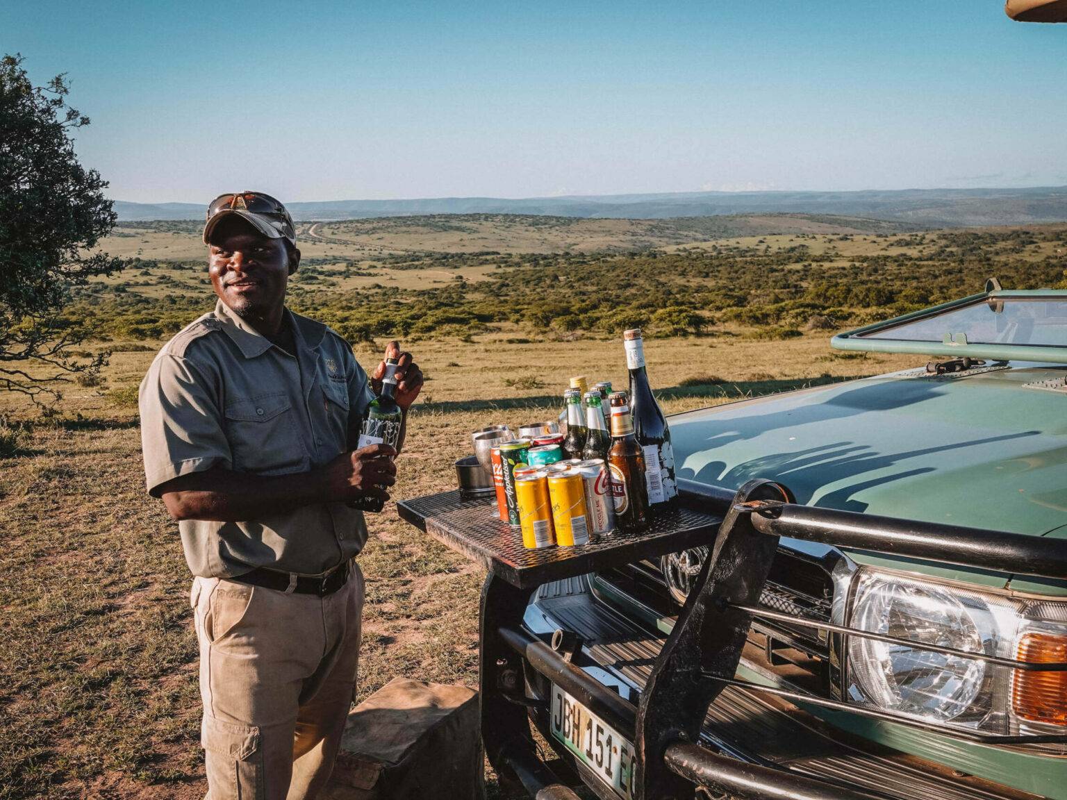 Ein Guide richtet Getränke vor seinem Auto an im Game Reserve in Südafrika.