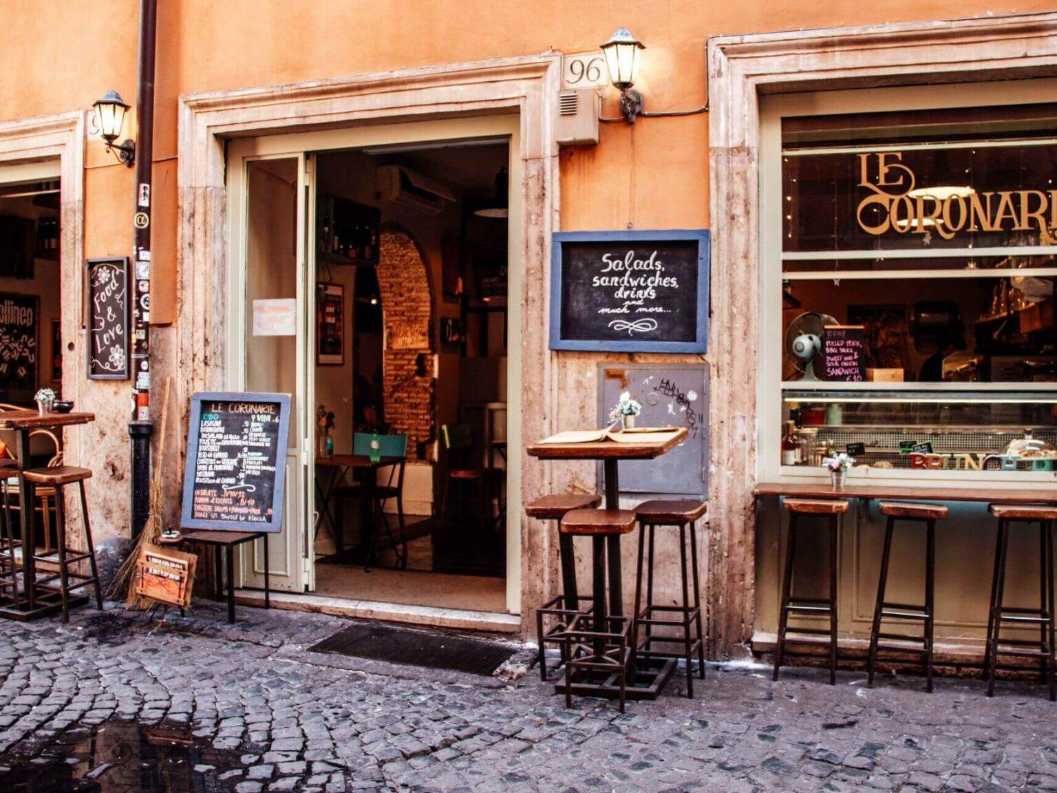 Blick auf das Restaurant Le Coronarie inb Rom mit Hochtischen und Barhockern im Vordergrund.