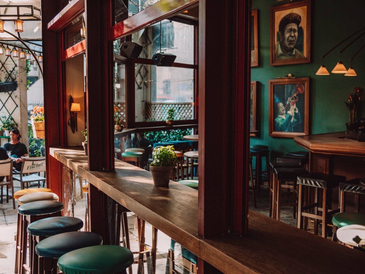 Dunkle Holztheken und Stühle und dunkelgrüne Wände zeichnen die Bar im Green Suites Boutique Hotel in Athen aus.