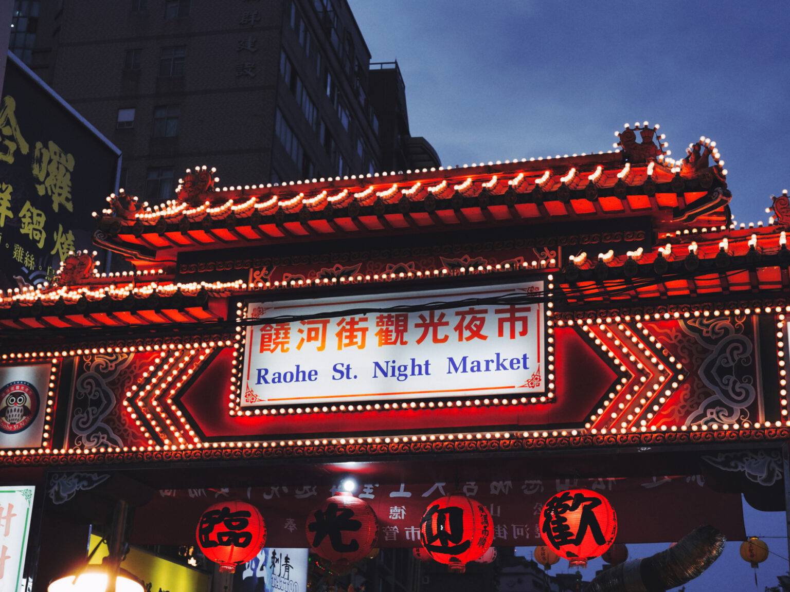 Ein rot beleuchtetes Tor führt zum Raohe Nachtmarkt in Taipeh.