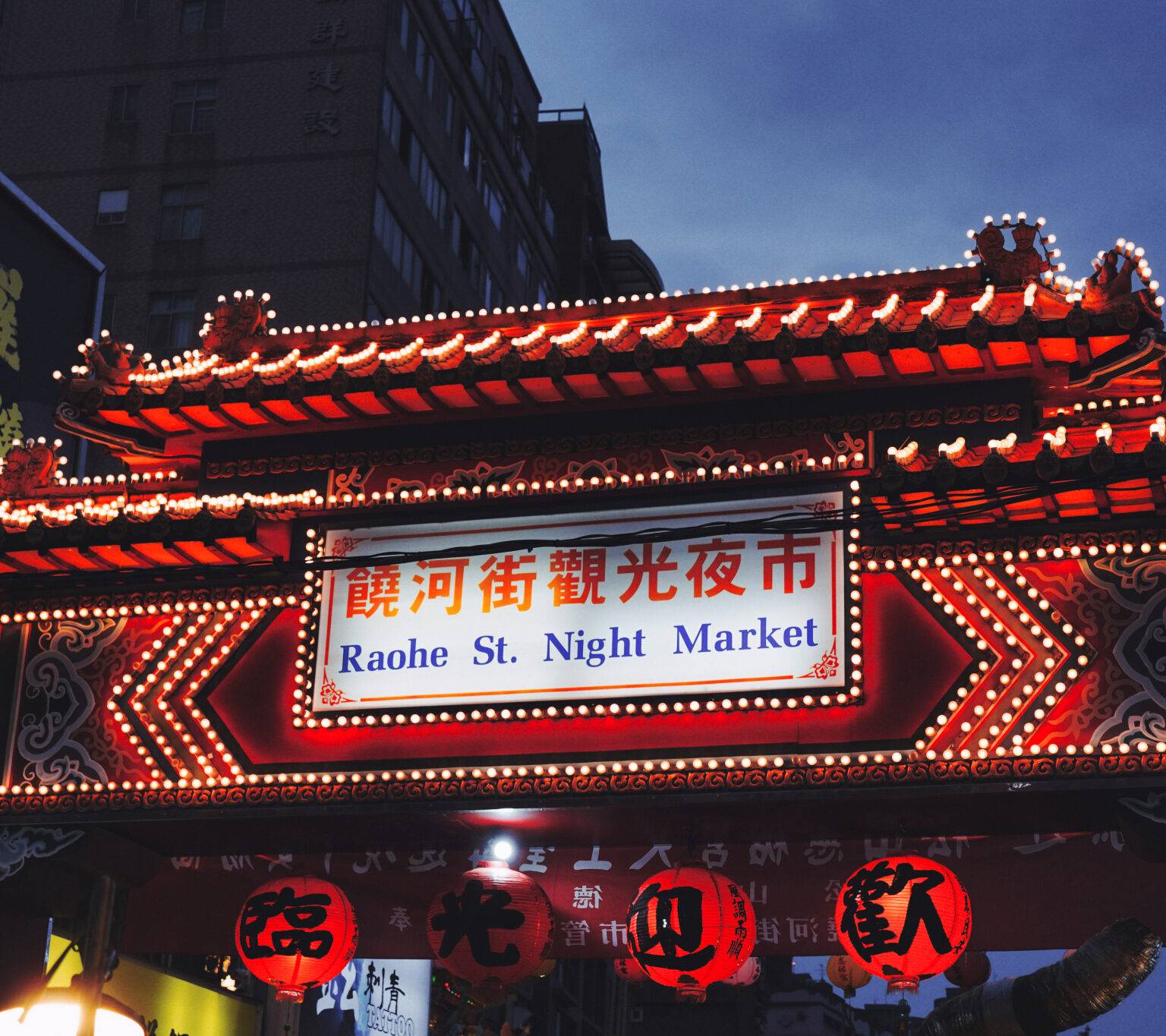 Ein rot beleuchtetes Tor führt zum Raohe Nachtmarkt in Taipeh.