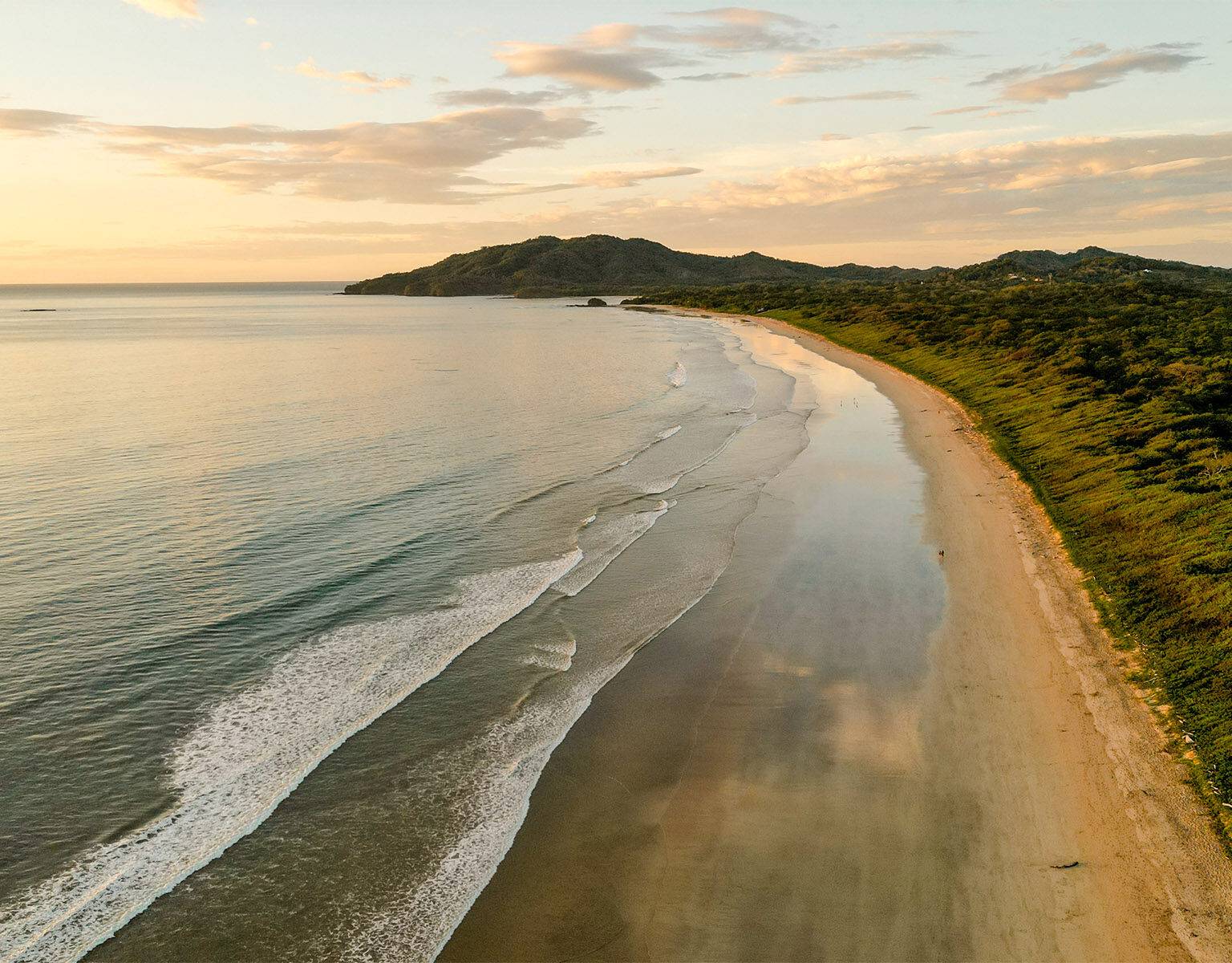 Das weitläufige Meer am Playa Grande Tamarindo mit grünen Bergen im Hintergrund.