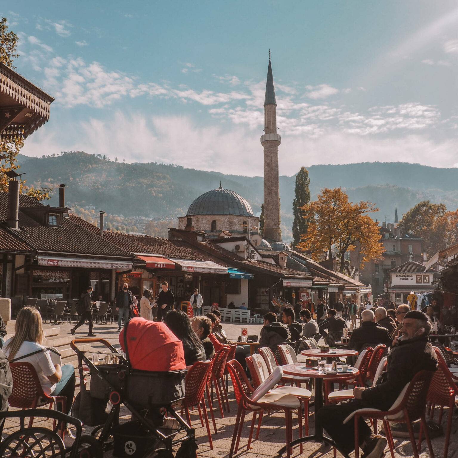 Einheimische und Touristen genießen auf einem Platz die Sonne in der Altstadt von Sarajevo.