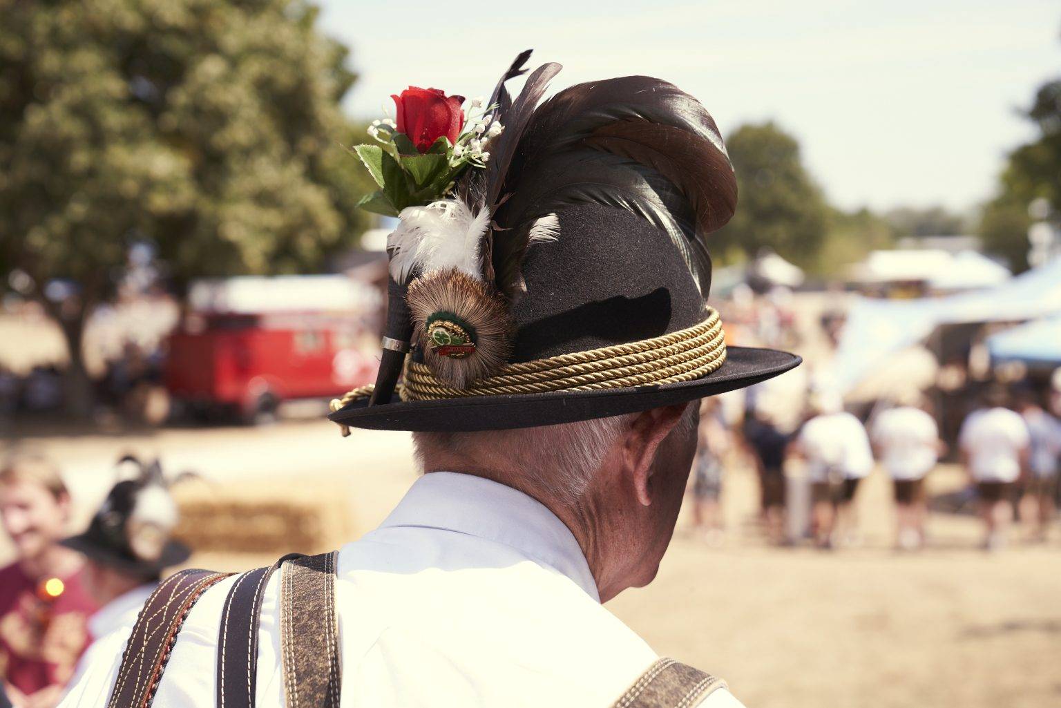 Ein Mann trägt einen traditionell bayerischer Hut mit Federn und Blumen.