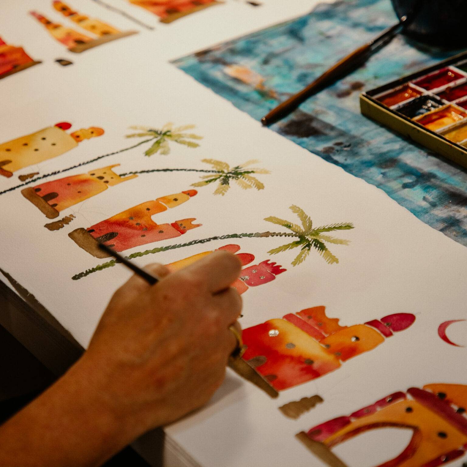 Eine Person malt mit Wasserfarben auf ein Papier.