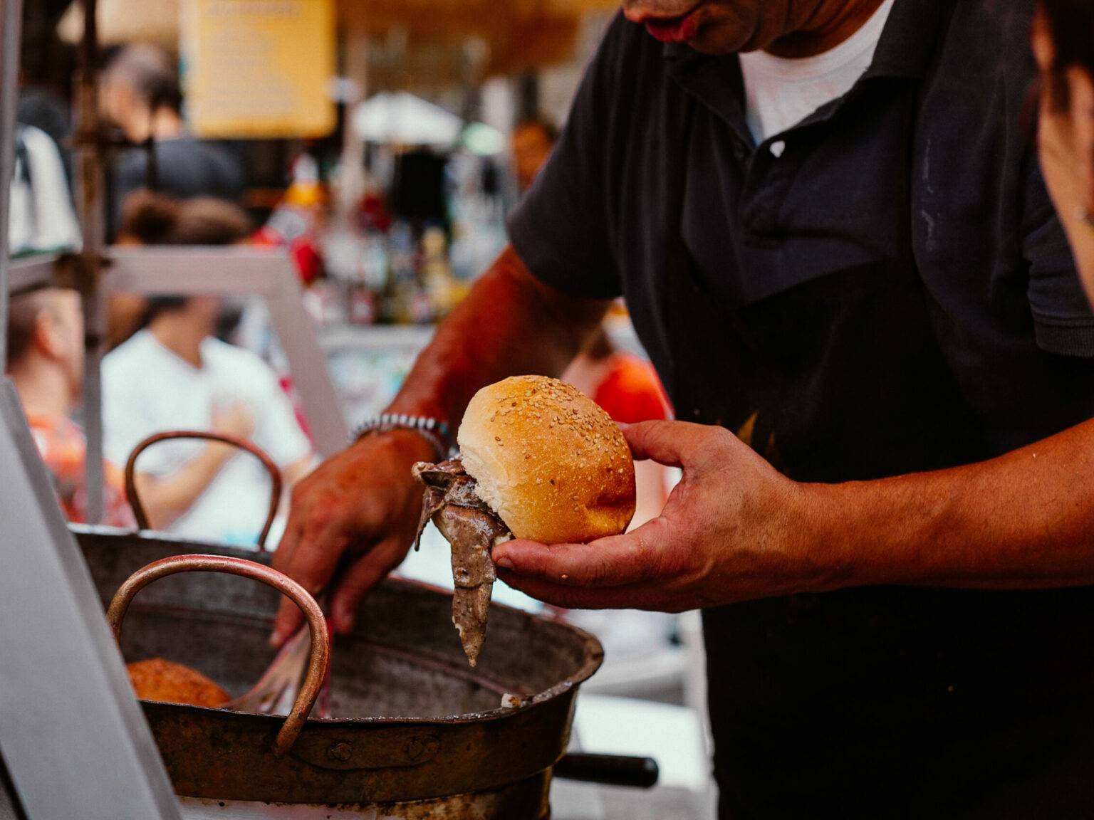 Eine Person bereitet auf einem Markt ein typisch sizilianisches Brötchen vor.