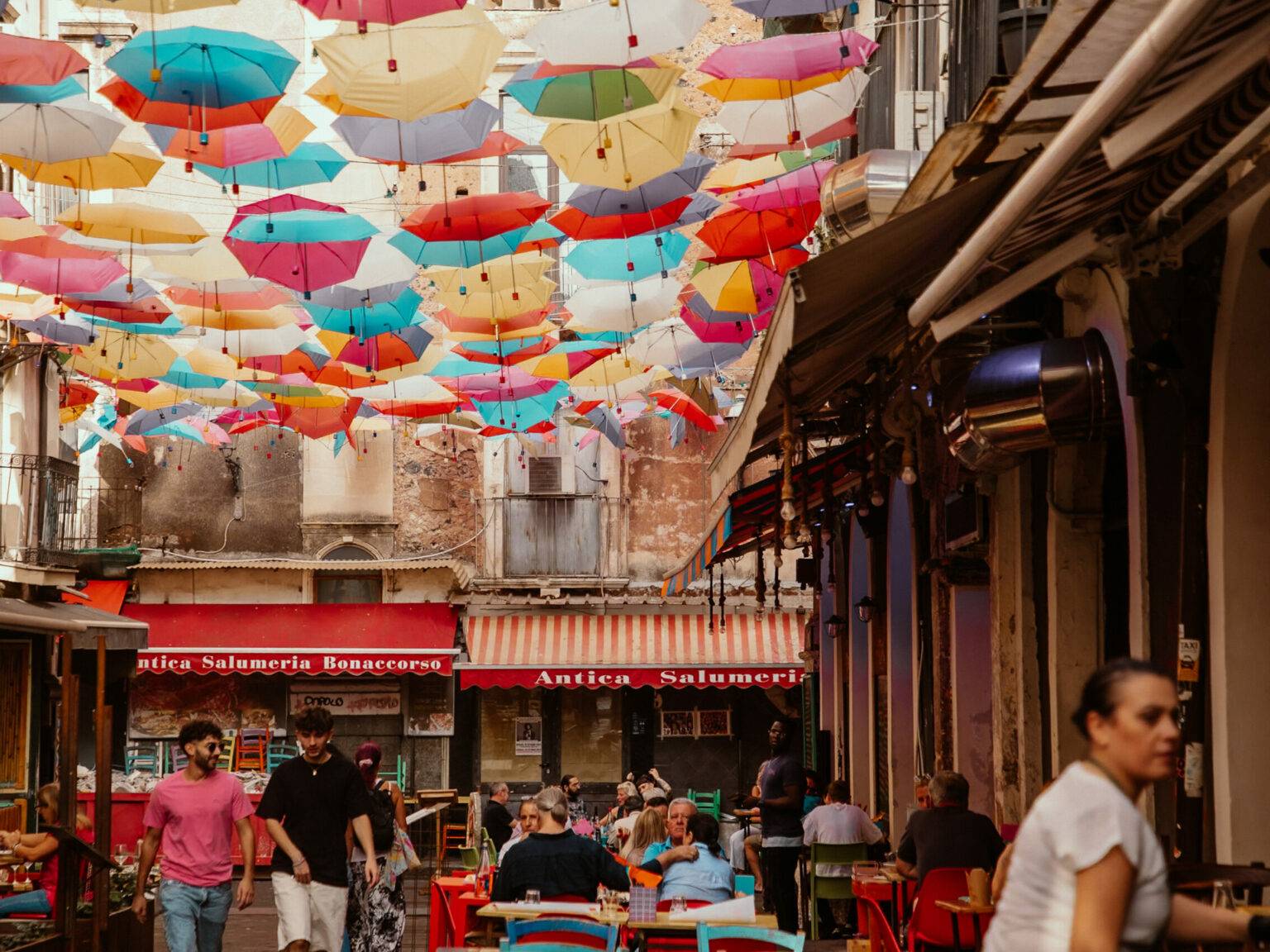 Eine bunte Gasse in Catania geschmückt mit Regenschirme.