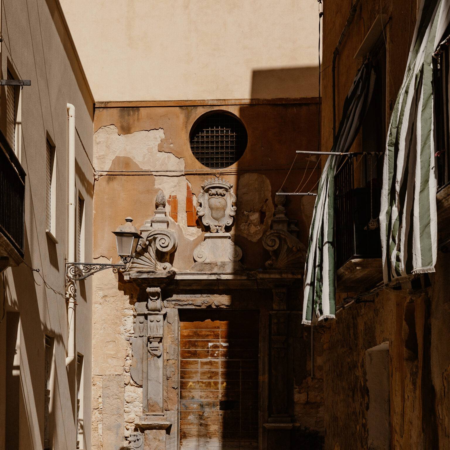 Eine Gasse in der Altstadt Trapani, an dem Balkonen wehen Vorhänge.