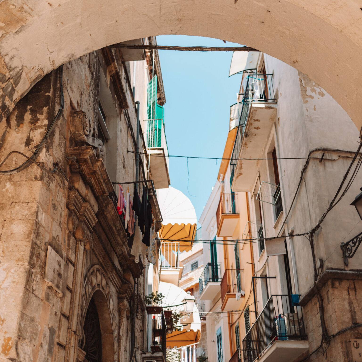 Ein Torbogen in einer Gasse in Bari, im Hintergrund alte Häuserfassaden.