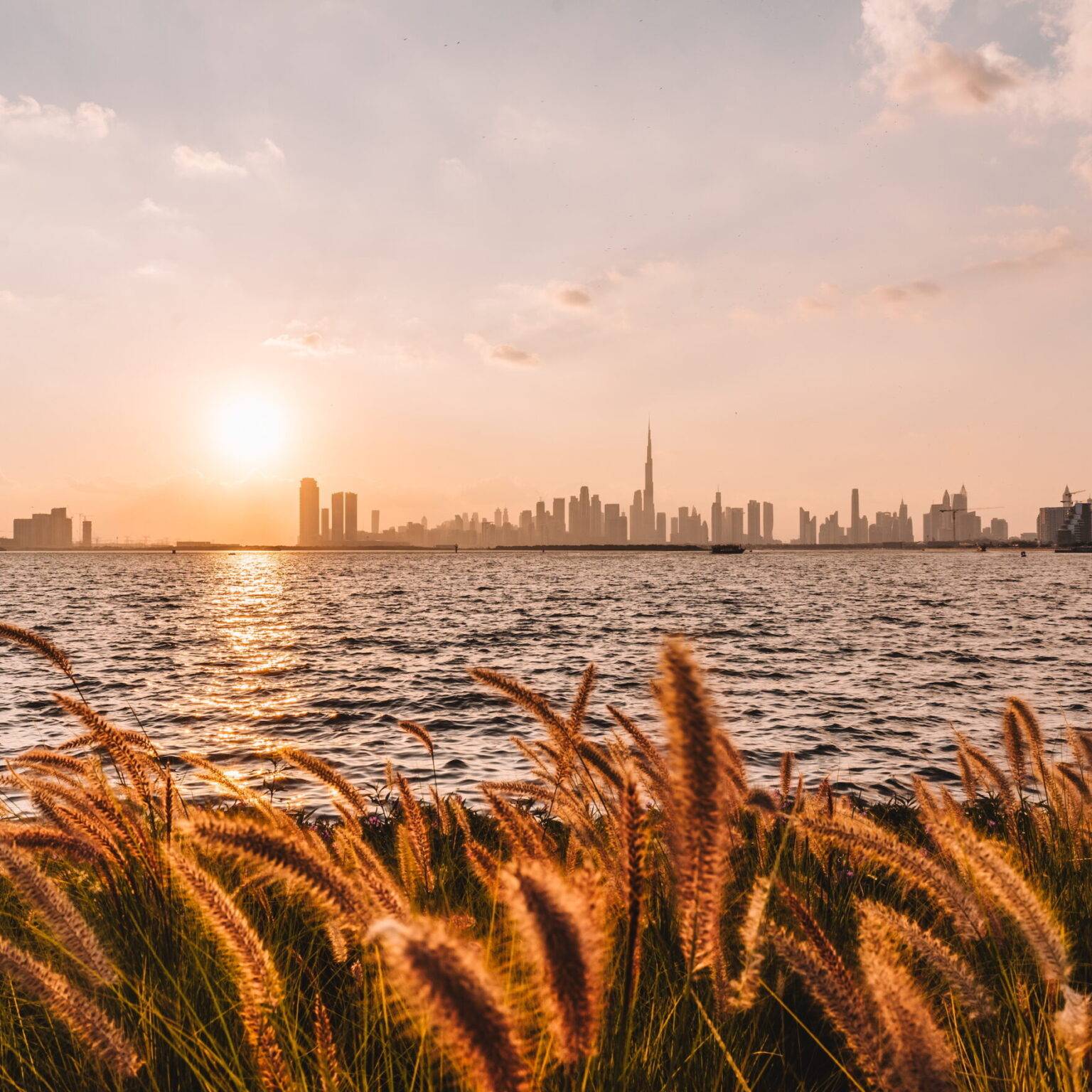 Der Creek Habour in Dubai mit der Skyline der Stadt im Hintergrund bei Sonnenuntergang.