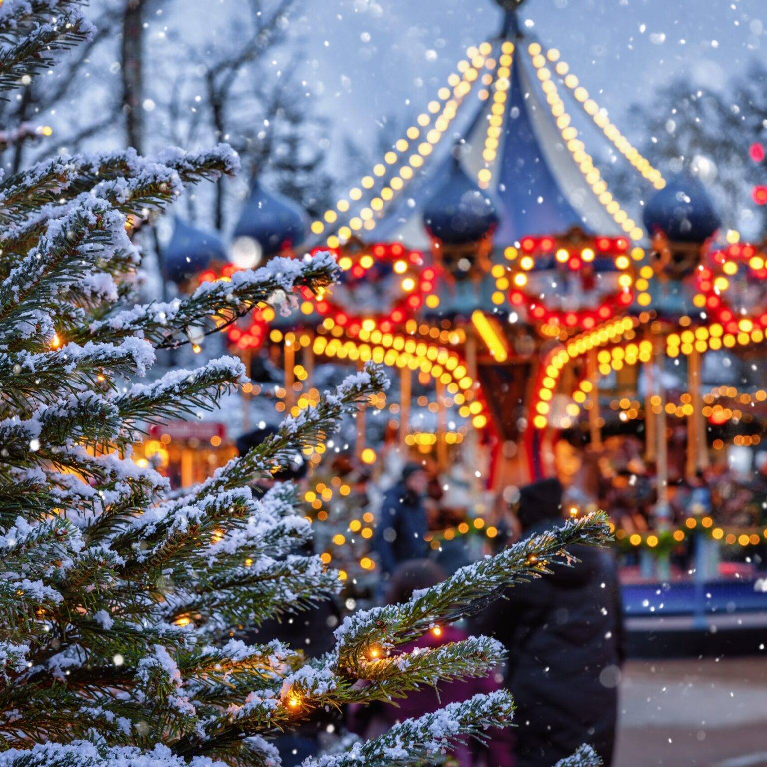 Das Karussell auf dem Tivoli Weihnachtsmarkt in Kopenhagen leuchtet im Schneetreiben.