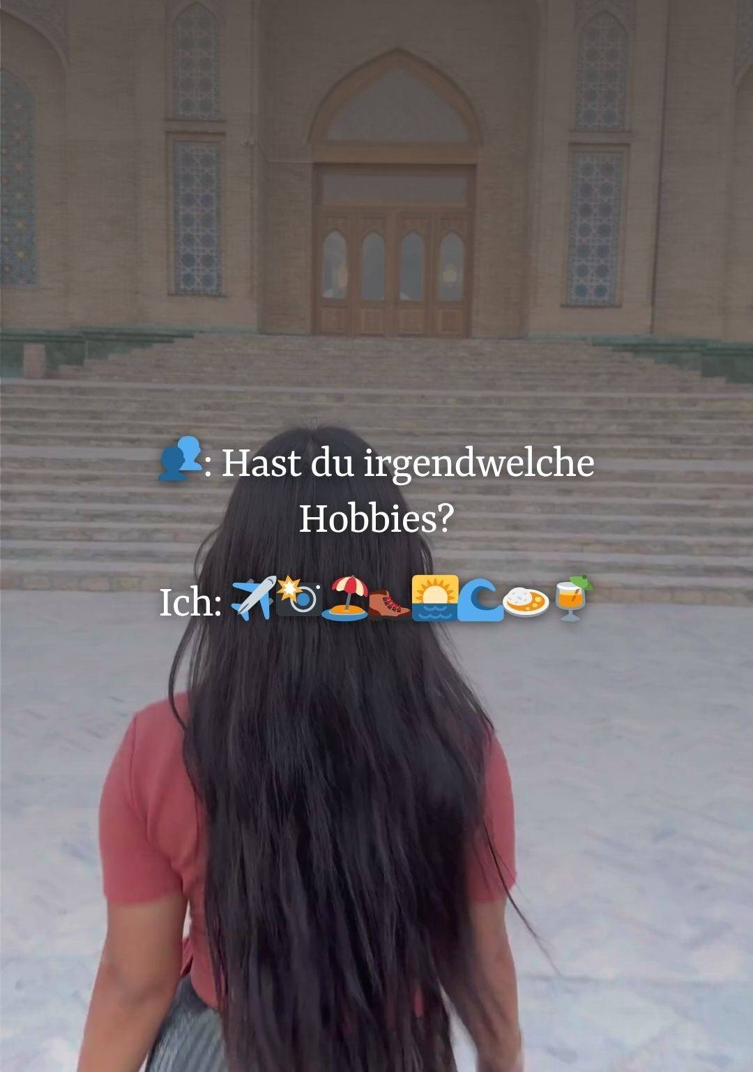 Eine Frau mit langen dunklen Haaren von hinten läuft auf eine steinerne Treppe vor einem orientalischen Torbogen zu. Davor steht "Hast du irgendwelche Hobbies? Ich: Reise-Emojis".